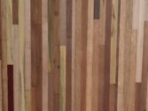A close-up of a wooden surface with vertical strips of various types and shades, including light, dark, and medium brown tones, showcasing a natural and textured appearance.
