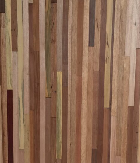 A close-up of a wooden surface with vertical strips of various types and shades, including light, dark, and medium brown tones, showcasing a natural and textured appearance.