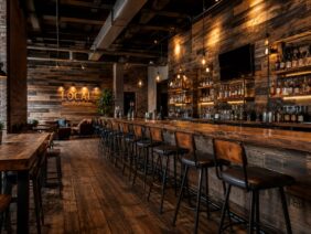 A bar and restaurant area with reclaimed wood walls, counters, tabletops, flooring.