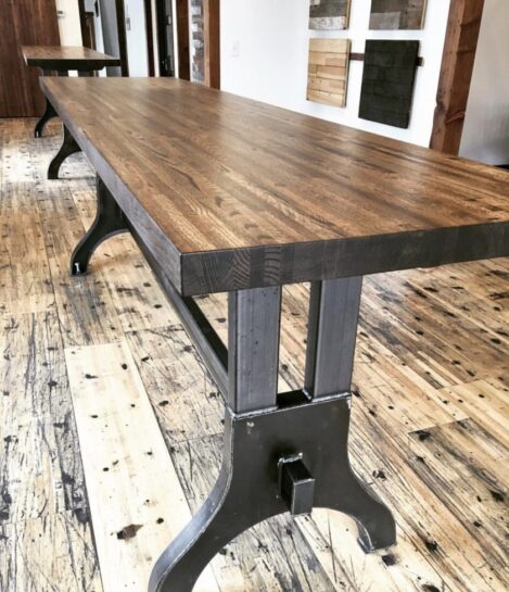 A long, rectangular wooden table with sturdy metal legs stands on a rustic hardwood floor. The tables smooth surface showcases the wood grain, contrasting with the industrial-style legs underneath. Another table is visible in the background. A long, rectangular wooden table with sturdy metal legs stands on a rustic hardwood floor. The tables smooth surface showcases the wood grain, contrasting with the industrial-style legs underneath. Another table is visible in the background.