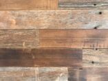 Close-up view of a wooden surface with various shades and textures. The planks are aligned horizontally and show natural grain patterns and knots, creating a rustic appearance.